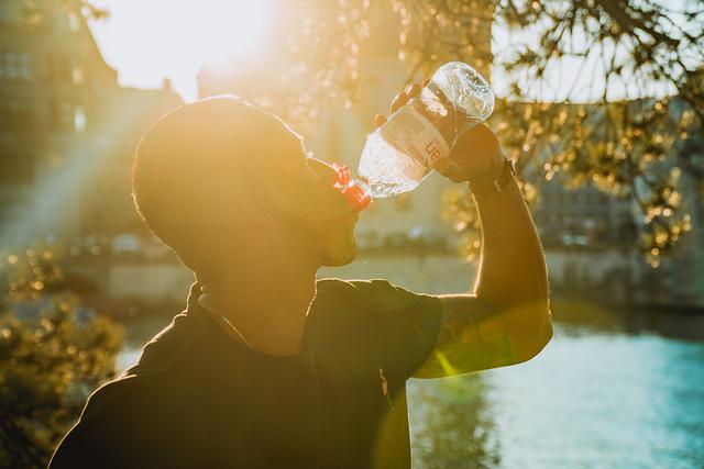 Athlete drinking water for hydration by a lake