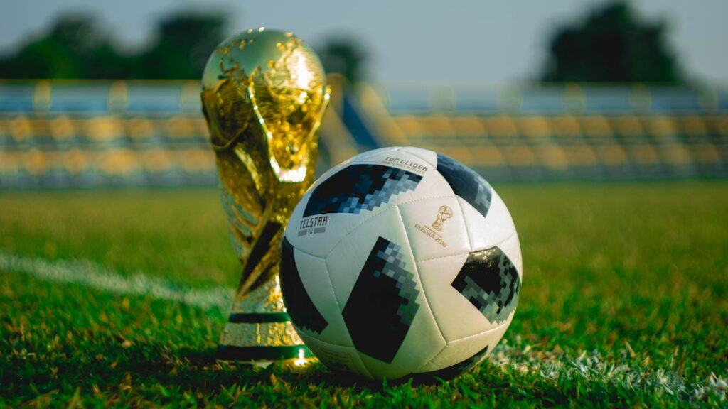 world cup trophy standing next to a football ona pitch