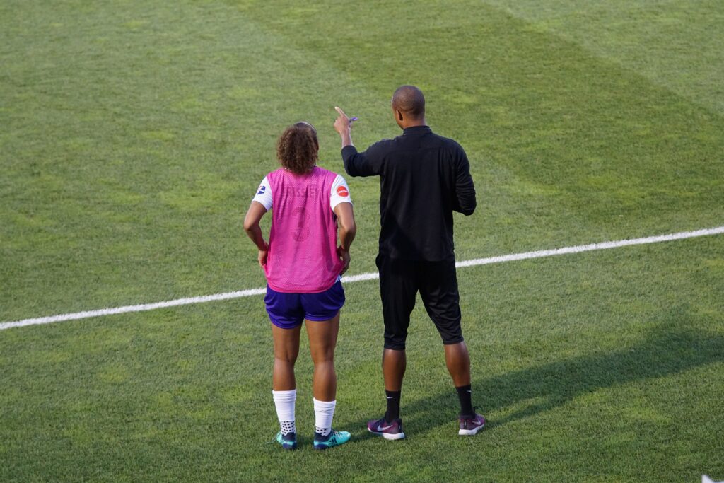 coach discussing the player potential with a soccer player on the grass