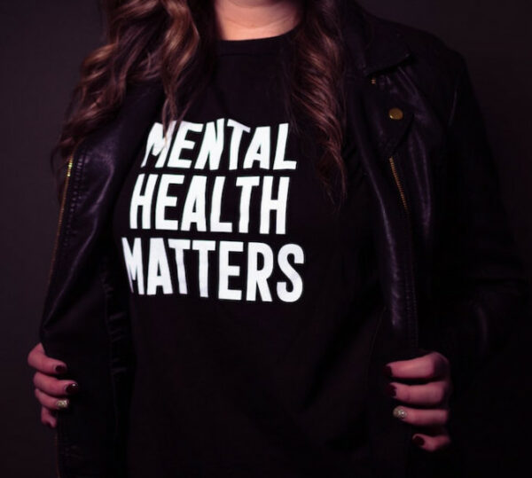 mental health matters written on a balck t-shirt displayed by a woman with long hair